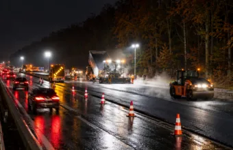 Nocne roboty drogowe na autostradzie E411 przy lesie, jeden pas ruchu otwarty