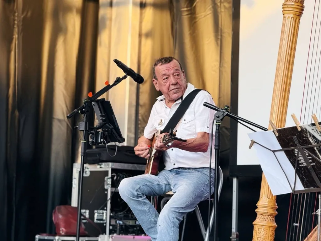 Dominique Piron podczas koncertu, obok harfa