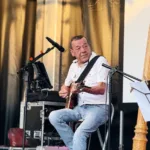 Dominique Piron podczas koncertu, obok harfa
