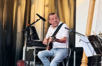 Dominique Piron podczas koncertu, obok harfa